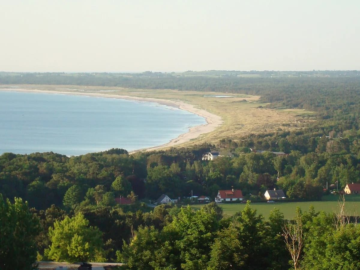 Coastal landscape overlooking Sejerø Bay with forest and houses.